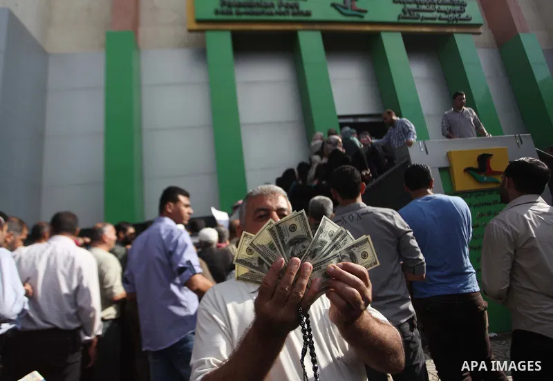 A Palestinian employee of the former Hamas government holds 1,200 US dollars in cash outside a post office in Gaza City on October 29, 2014 after receiving part of his wages that has been delayed for months. The Palestin...