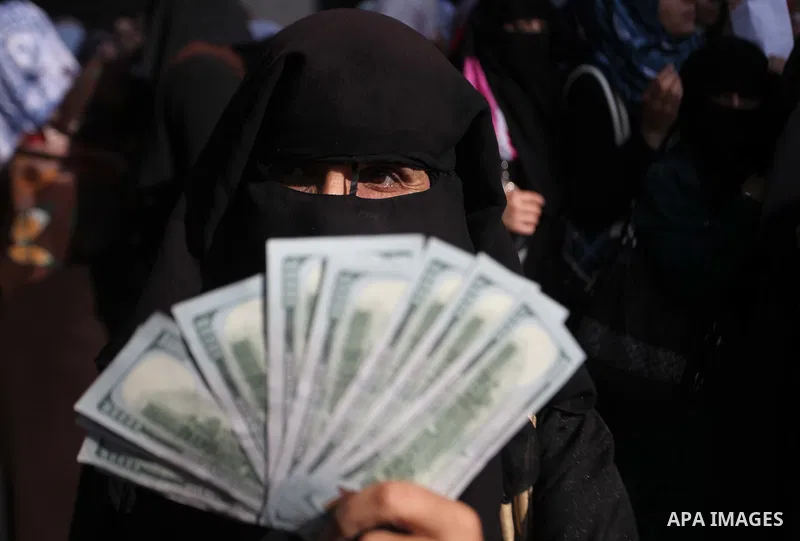 A Palestinian employee of the former Hamas government holds 1,200 US dollars in cash outside a post office in Gaza City on October 29, 2014 after receiving part of his wages that has been delayed for months. The Palestin...