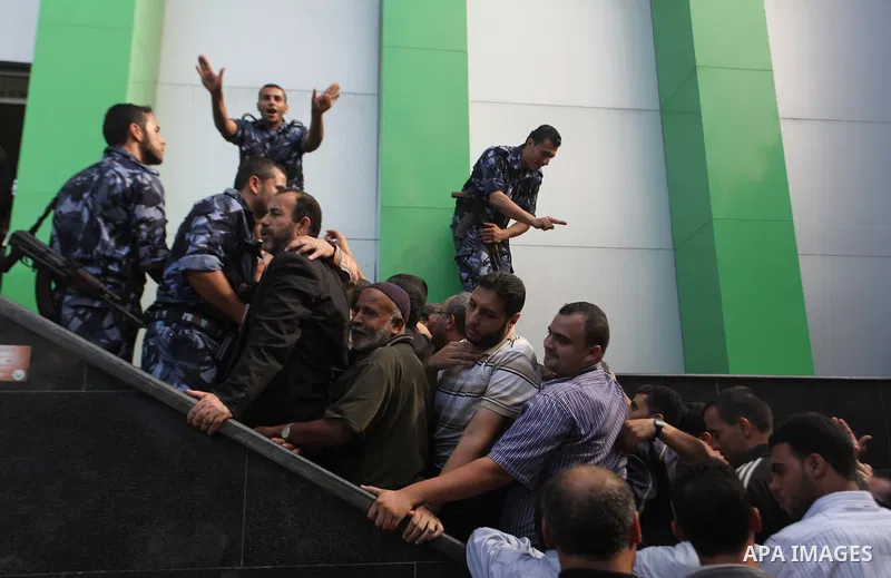 Employees of former Palestinian government in Gaza Strip wait to receive their salaries at a Post Office in Gaza city on October 29, 2014. The Palestinian national unity government headed by prime minister Rami Hamdallah...