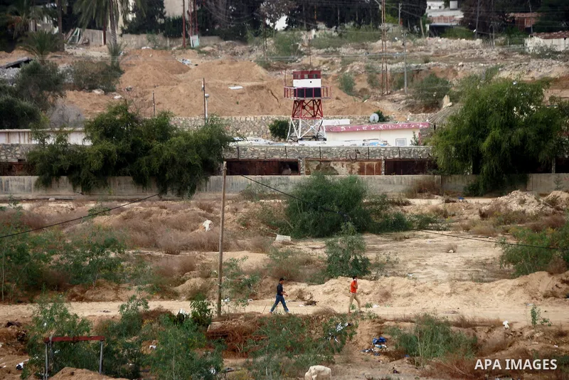 Palestinians walk near the border as Egyptian security forces take part in a military operation to demolish some buildings in the Egyptian city of Rafah near the border with southern Gaza Strip October 29, 2014, as Egypt...