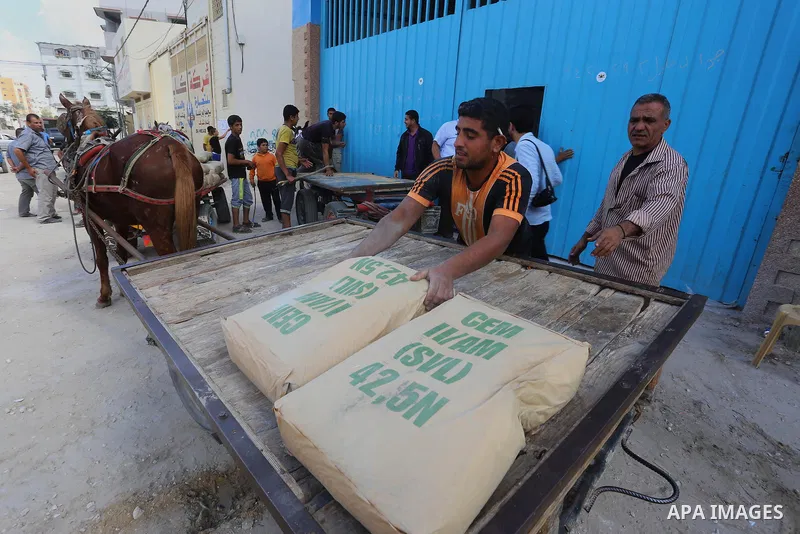 Palestinian workers carry bags of cement at center in al-Shejaiya neighbourhood in the east of Gaza City, October 30, 2014. More than 100,000 Gaza residents are still homeless. According to reports, Israel has only deliv...