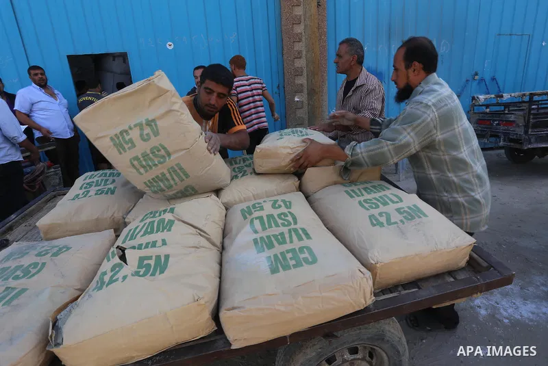 Palestinian workers carry bags of cement at center in al-Shejaiya neighbourhood in the east of Gaza City, October 30, 2014. More than 100,000 Gaza residents are still homeless. According to reports, Israel has only deliv...