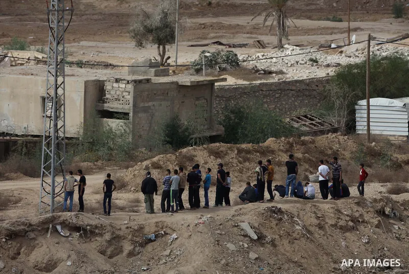Palestinians look on as Egyptian soldiers take part in a military operation in the Egyptian city of Rafah, near the border with the southern Gaza Strip on October 30, 2014, as Egypt began setting up a buffer zone along t...