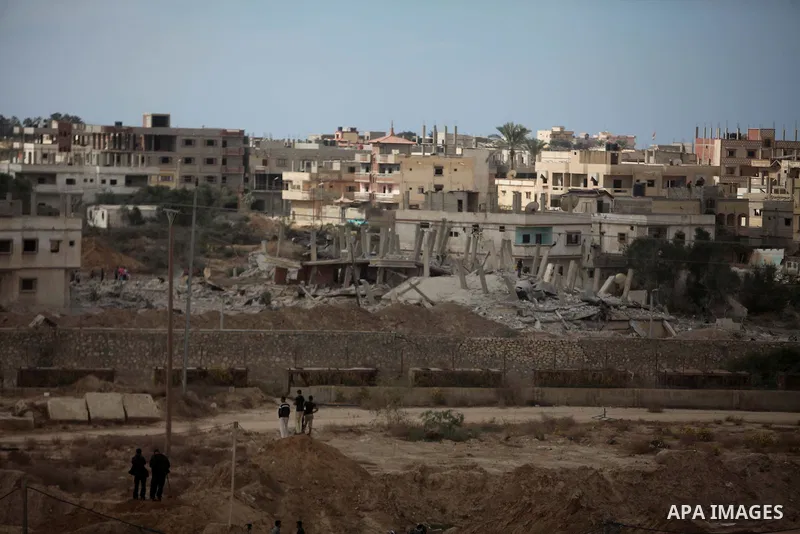 Palestinians look on as Egyptian soldiers take part in a military operation in the Egyptian city of Rafah, near the border with the southern Gaza Strip on October 30, 2014, as Egypt began setting up a buffer zone along t...