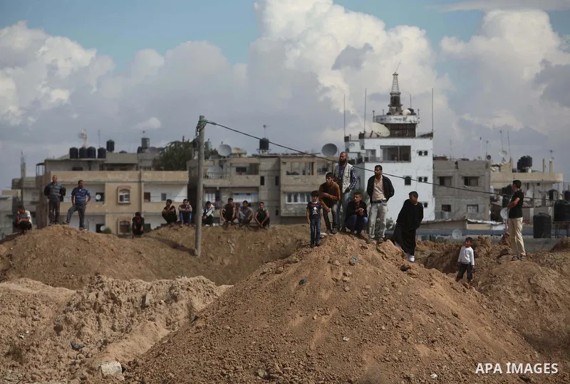 Palestinians look on as Egyptian soldiers take part in a military operation in the Egyptian city of Rafah, near the border with the southern Gaza Strip on October 30, 2014, as Egypt began setting up a buffer zone along t...