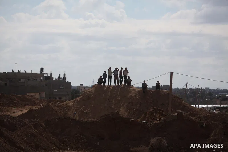 Palestinians look on as Egyptian soldiers take part in a military operation in the Egyptian city of Rafah, near the border with the southern Gaza Strip on October 30, 2014, as Egypt began setting up a buffer zone along t...