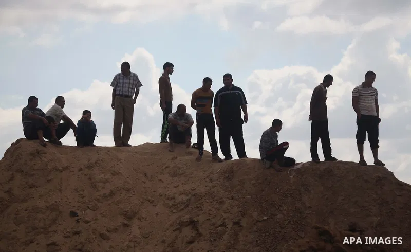 Palestinians look on as Egyptian soldiers take part in a military operation in the Egyptian city of Rafah, near the border with the southern Gaza Strip on October 30, 2014, as Egypt began setting up a buffer zone along t...