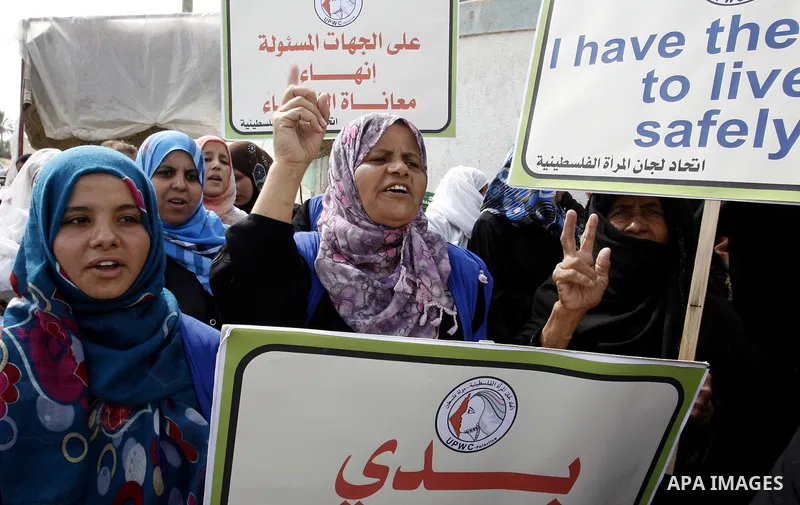 Palestinian women hold placards during a protest in solidarity with women who displaced from their homes during the seven weeks Israeli offensive on Gaza Strip, outside a UN school, in Rafah in the southern Gaza Strip, O...