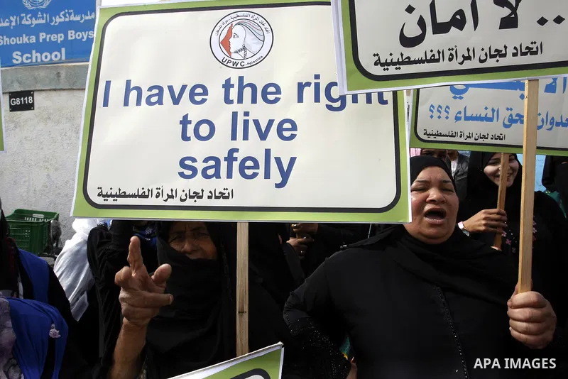 Palestinian women hold placards during a protest in solidarity with women who displaced from their homes during the seven weeks Israeli offensive on Gaza Strip, outside a UN school, in Rafah in the southern Gaza Strip, O...