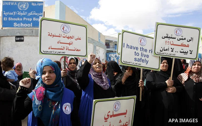 Palestinian women hold placards during a protest in solidarity with women who displaced from their homes during the seven weeks Israeli offensive on Gaza Strip, outside a UN school, in Rafah in the southern Gaza Strip, O...
