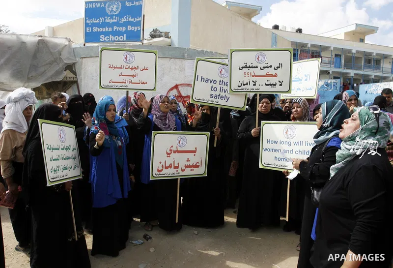 Palestinian women hold placards during a protest in solidarity with women who displaced from their homes during the seven weeks Israeli offensive on Gaza Strip, outside a UN school, in Rafah in the southern Gaza Strip, O...