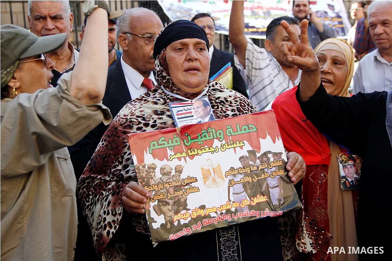 Pro-deposed president Hosni Mubarak Egyptians hold placards during a protest demanding the trial of the revolution leaders, outside the court of cassation, in Cairo on October 30, 2014. Photo by Amr Sayed