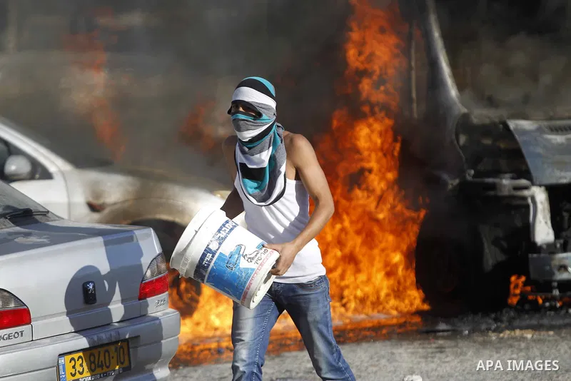 A masked Palestinian youth tries to extinguish the fire in cars during clashes with Israeli security forces after Moataz Higazi was shot in east Jerusalem October 30, 2014. Israeli police shot and killed Higazi suspected...