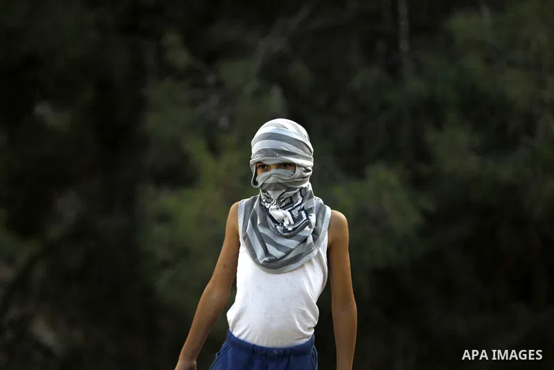 A masked Palestinian youth looks on during clashes with Israeli security forces after Moataz Higazi was shot in east Jerusalem October 30, 2014. Israeli police shot and killed Higazi suspected of trying to kill a hard-li...