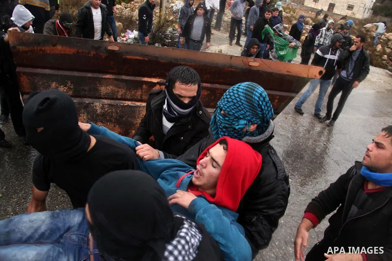 Palestinian youths carry a wounded protester during clashes with Israeli security forces in a protest against Israeli restrictions at the Al-Aqsa Mosque compound, and in solidarity with the people in Jerusalem, in the We...