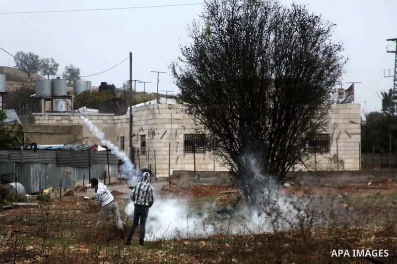 A Palestinian youth throws back a tear gas canister towards Israeli security forces during clashes in a protest against Israeli restrictions at the Al-Aqsa Mosque compound, and in solidarity with the people in Jerusalem,...