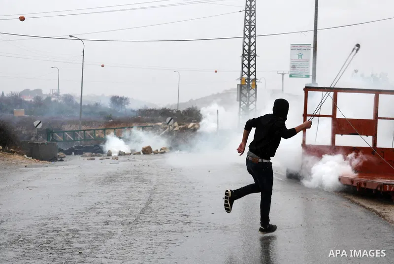 A Palestinian youth throws stones towards Israeli security forces during clashes in a protest against Israeli restrictions at the Al-Aqsa Mosque compound, and in solidarity with the people in Jerusalem, in the West Bank...