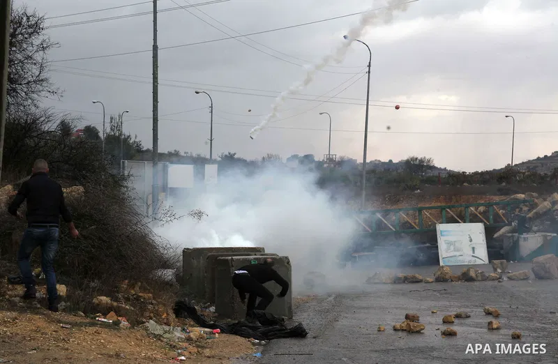 A Palestinian youth throws stones towards Israeli security forces during clashes in a protest against Israeli restrictions at the Al-Aqsa Mosque compound, and in solidarity with the people in Jerusalem, in the West Bank...