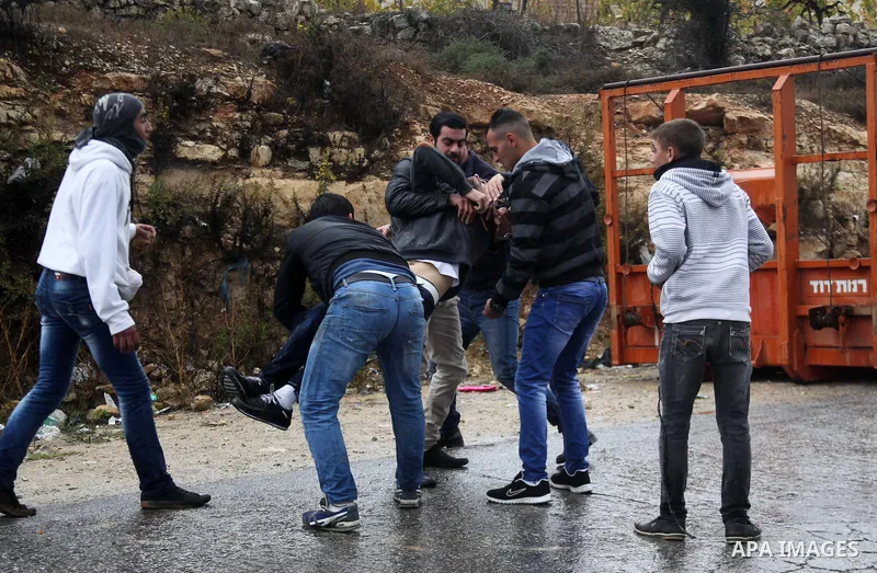 Palestinian youths carry a wounded protester during clashes with Israeli security forces in a protest against Israeli restrictions at the Al-Aqsa Mosque compound, and in solidarity with the people in Jerusalem, in the We...