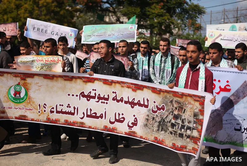 Palestinian supporters of Hamas movement hold banners during a protest organized by the owners of houses which were destroyed by Israeli shelling during the most recent conflict between Israel and Hamas, calling for reco...