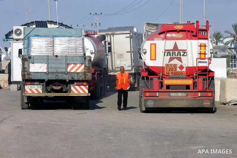 A Palestinian worker walks past trucks loaded with supplies that entered the Gaza Strip from Israel through the Kerem Shalom crossing in Rafah in the southern Gaza Strip on November 5, 2014. UN peace envoy Robert Serry a...