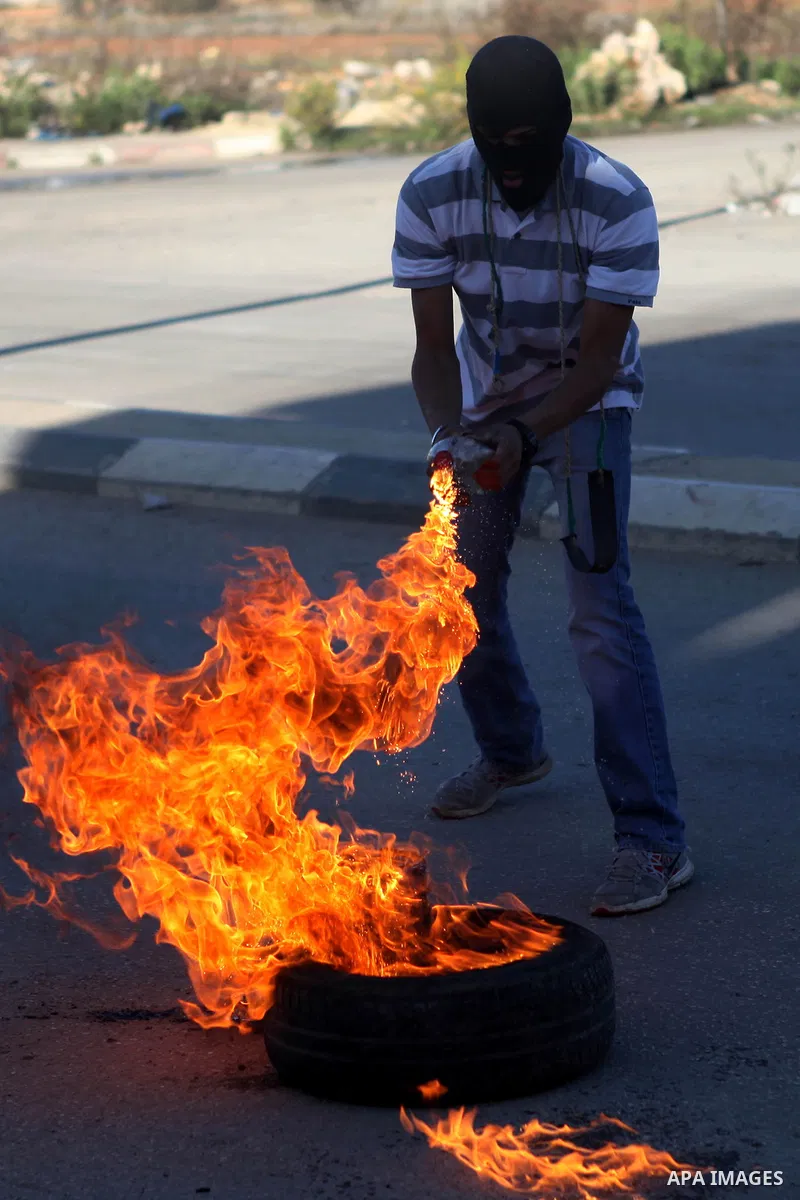 A Palestinian student of the BirZeit University burns a tire during clashes with Israeli security forces following an anti-Israel demonstration over the recent entry restrictions to the al-Aqsa mosque, outside Israel's O...