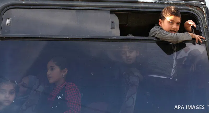 children look at young Palestinians from Hamas's "popular army" during a military graduation ceremony in Jabaliya refugee camp in the northern Gaza Strip November 7, 2014. Hamas recently formed a "popular army" for young...