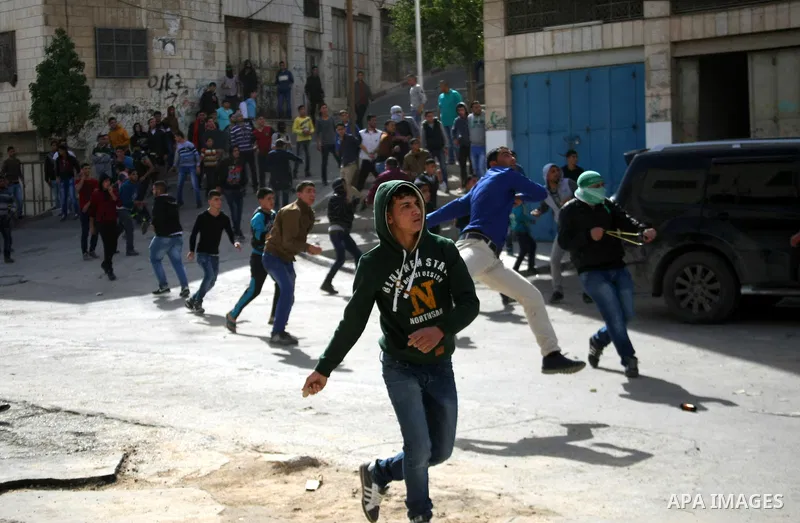 Palestinian protesters throw stones towards Israeli security forces during clashes following a protest against Israel's restrictions at the Al-Aqsa Mosque in Jerusalem, in the West Bank city of Hebron, November 14, 2014....