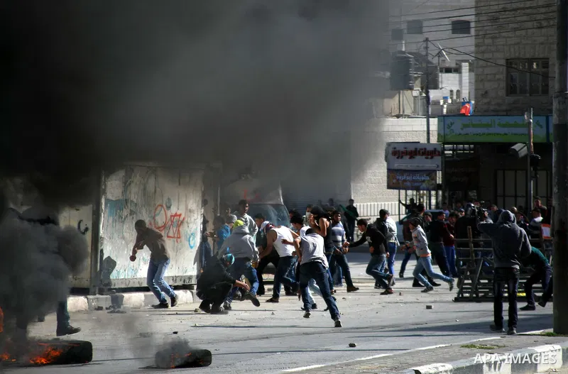 Palestinian protesters throw stones towards Israeli security forces during clashes following a protest against Israel's restrictions at the Al-Aqsa Mosque in Jerusalem, in the West Bank city of Hebron, November 14, 2014....