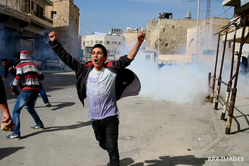 Palestinian protesters run for cover from tear gas fired by Israeli security forces during clashes following a protest against Israel's restrictions at the Al-Aqsa Mosque in Jerusalem, in the West Bank city of Hebron, No...