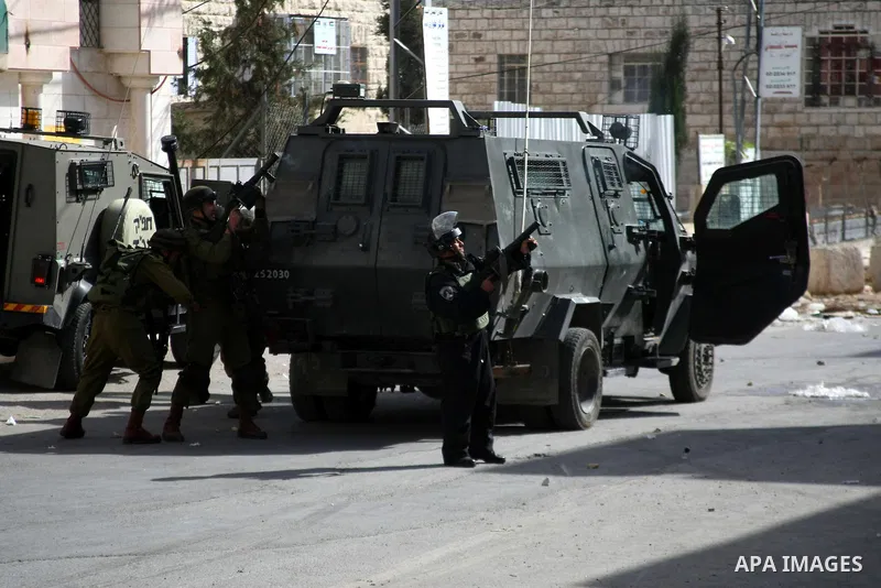 A member of Israeli security forces fires tear gas towards Palestinian protesters during clashes following a protest against Israel's restrictions at the Al-Aqsa Mosque in Jerusalem, in the West Bank city of Hebron, Nove...