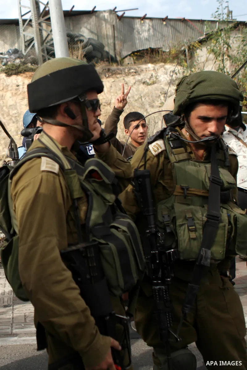 A Palestinian protester (background) flashes a victory sign as Israeli security forces take position during a demonstration against Israel's restrictions at the Al-Aqsa Mosque in Jerusalem, in Hizma village near the West...