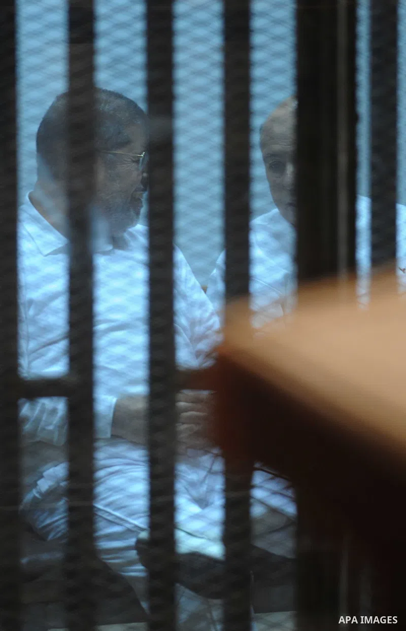 Egypt's deposed Islamist president Mohamed Morsi gestures inside the defendant's cage during his trial in cooperation cause in Cairo on Nov. 15, 2014. Morsi is being tried at a courtroom in the Police Academy in New Cair...
