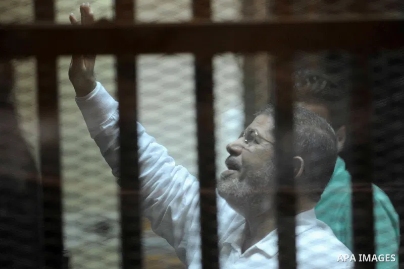 Egypt's deposed Islamist president Mohamed Morsi gestures inside the defendant's cage during his trial in cooperation cause in Cairo on Nov. 15, 2014. Morsi is being tried at a courtroom in the Police Academy in New Cair...