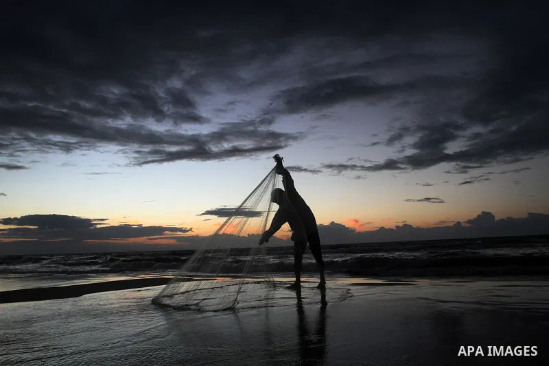 A Palestinian fisherman throws his net into the sea at the beach of Gaza City on Nov. 16, 2014. Photo by Yasser Qudih