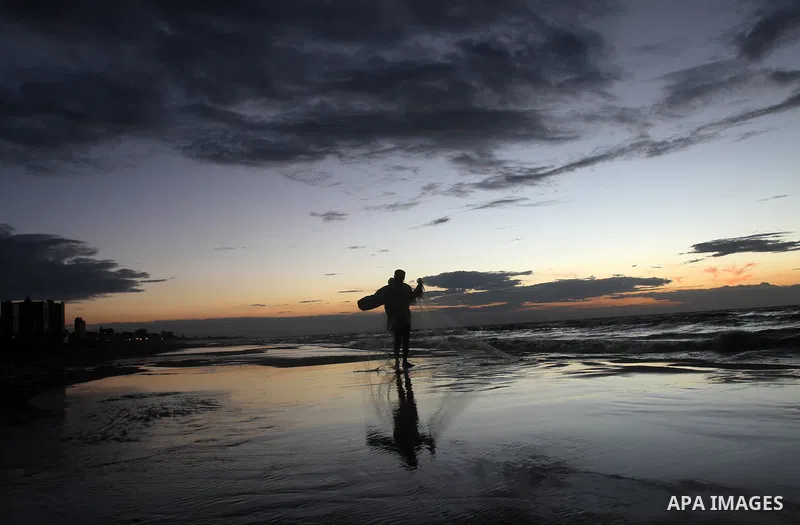 A Palestinian fisherman throws his net into the sea at the beach of Gaza City on Nov. 16, 2014. Photo by Yasser Qudih