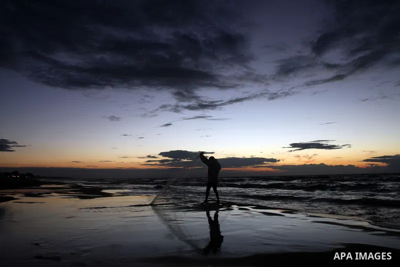 A Palestinian fisherman throws his net into the sea at the beach of Gaza City on Nov. 16, 2014. Photo by Yasser Qudih