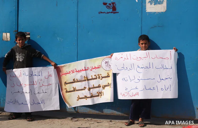 Palestinians hold banners during a protest to demand for reconstruction of the houses which were destroyed by Israeli shelling during the most recent conflict between Israel and Hamas, in front of the Supply Center for U...