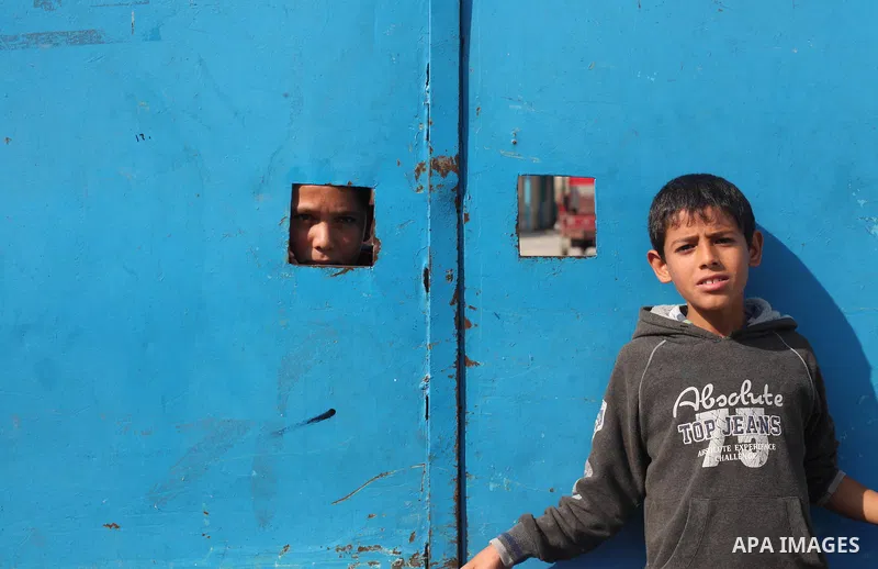 A Palestinian boy looks through perforate a gate as he takes part a protest to demand for reconstruction of the house which was destroyed by Israeli shelling during the most recent conflict between Israel and Hamas, in f...