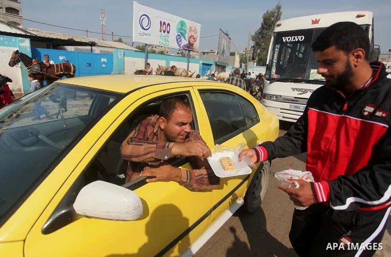 A Palestinian man distributes sweets as he celebrates with others an attack on a Jerusalem synagogue, in Gaza city November 18, 2014. Two Palestinians armed with a meat cleaver and a gun killed four people in a Jerusalem...