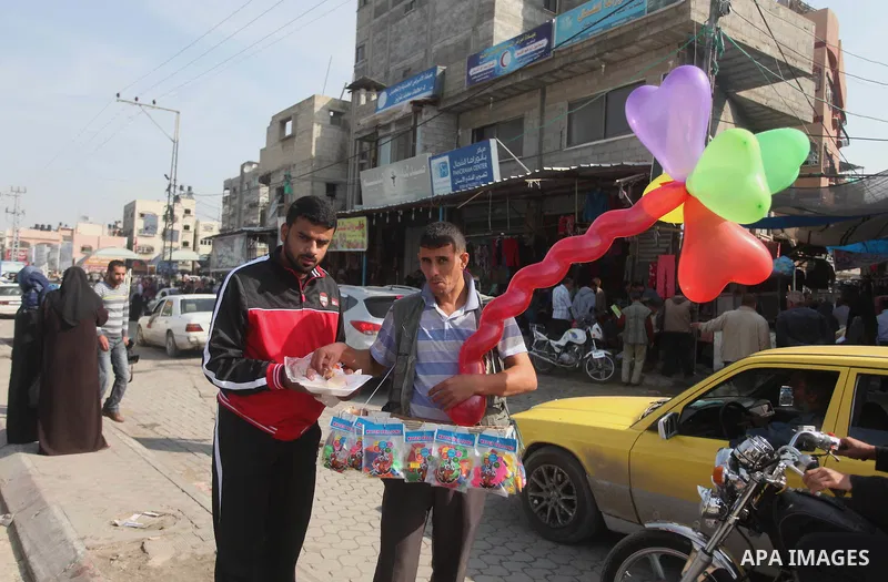 A Palestinian man distributes sweets as he celebrates with others an attack on a Jerusalem synagogue, in Gaza city November 18, 2014. Two Palestinians armed with a meat cleaver and a gun killed four people in a Jerusalem...