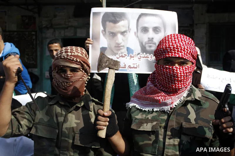 Masked Palestinians hold axes and a gun as they celebrate with others an attack on a Jerusalem synagogue, in Rafah in the southern Gaza Strip November 18, 2014. Two Palestinians armed with a meat cleaver and a gun killed...