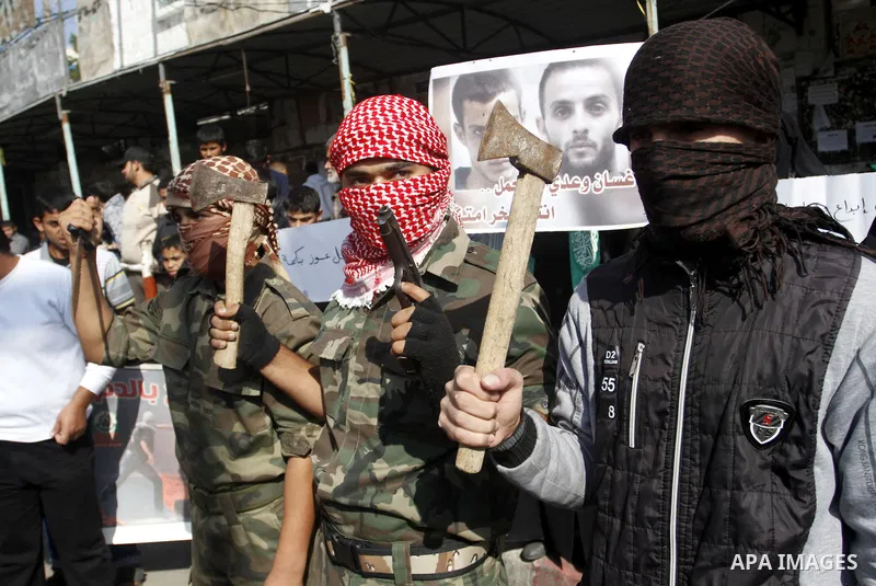 Masked Palestinians hold axes and a gun as they celebrate with others an attack on a Jerusalem synagogue, in Rafah in the southern Gaza Strip November 18, 2014. Two Palestinians armed with a meat cleaver and a gun killed...