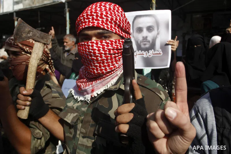 Masked Palestinians hold axes and a gun as they celebrate with others an attack on a Jerusalem synagogue, in Rafah in the southern Gaza Strip November 18, 2014. Two Palestinians armed with a meat cleaver and a gun killed...