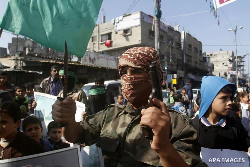 Masked Palestinians hold axes and a gun as they celebrate with others an attack on a Jerusalem synagogue, in Rafah in the southern Gaza Strip November 18, 2014. Two Palestinians armed with a meat cleaver and a gun killed...