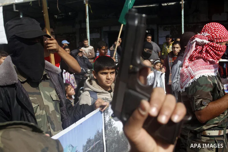 A Masked Palestinian holds a gun as he celebrates with others an attack on a Jerusalem synagogue, in Rafah in the southern Gaza Strip November 18, 2014. Two Palestinians armed with a meat cleaver and a gun killed four pe...