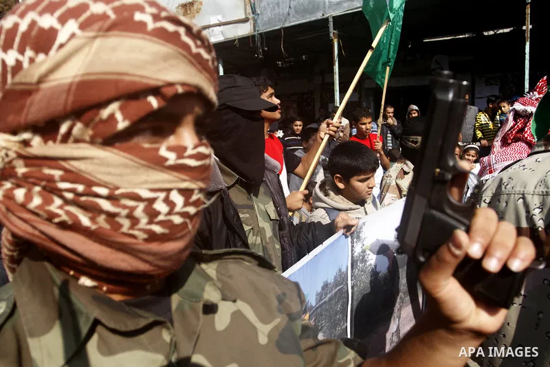 Masked Palestinians hold axes and a gun as they celebrate with others an attack on a Jerusalem synagogue, in Rafah in the southern Gaza Strip November 18, 2014. Two Palestinians armed with a meat cleaver and a gun killed...