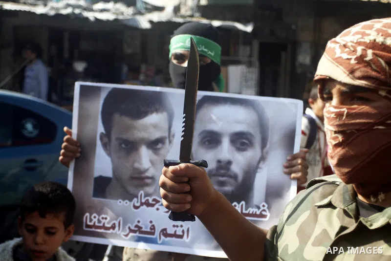 Masked Palestinians hold axes and a gun as they celebrate with others an attack on a Jerusalem synagogue, in Rafah in the southern Gaza Strip November 18, 2014. Two Palestinians armed with a meat cleaver and a gun killed...
