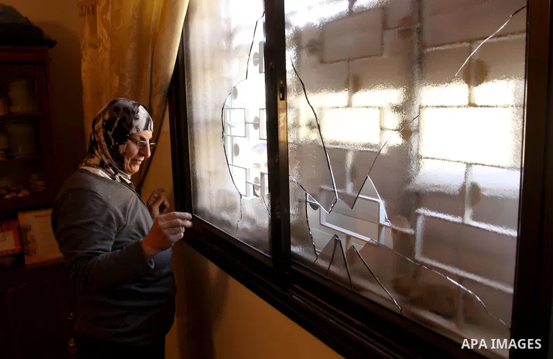 A Palestinian woman inspects a broken window of her house by Israeli settlers near the village of Burin, south of the West Bank city of Nablus, on Nov. 19, 2014. Photo by Nedal Eshtayah