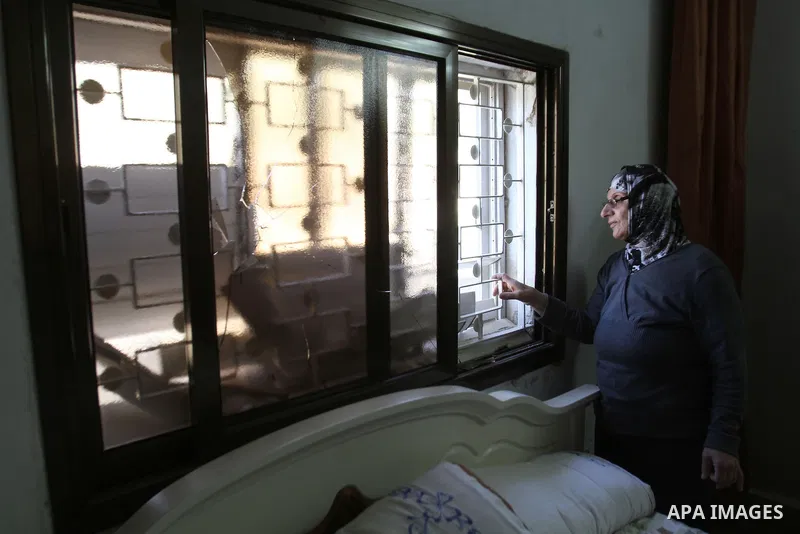 A Palestinian woman inspects a broken window of her house by Israeli settlers near the village of Burin, south of the West Bank city of Nablus, on Nov. 19, 2014. Photo by Nedal Eshtayah